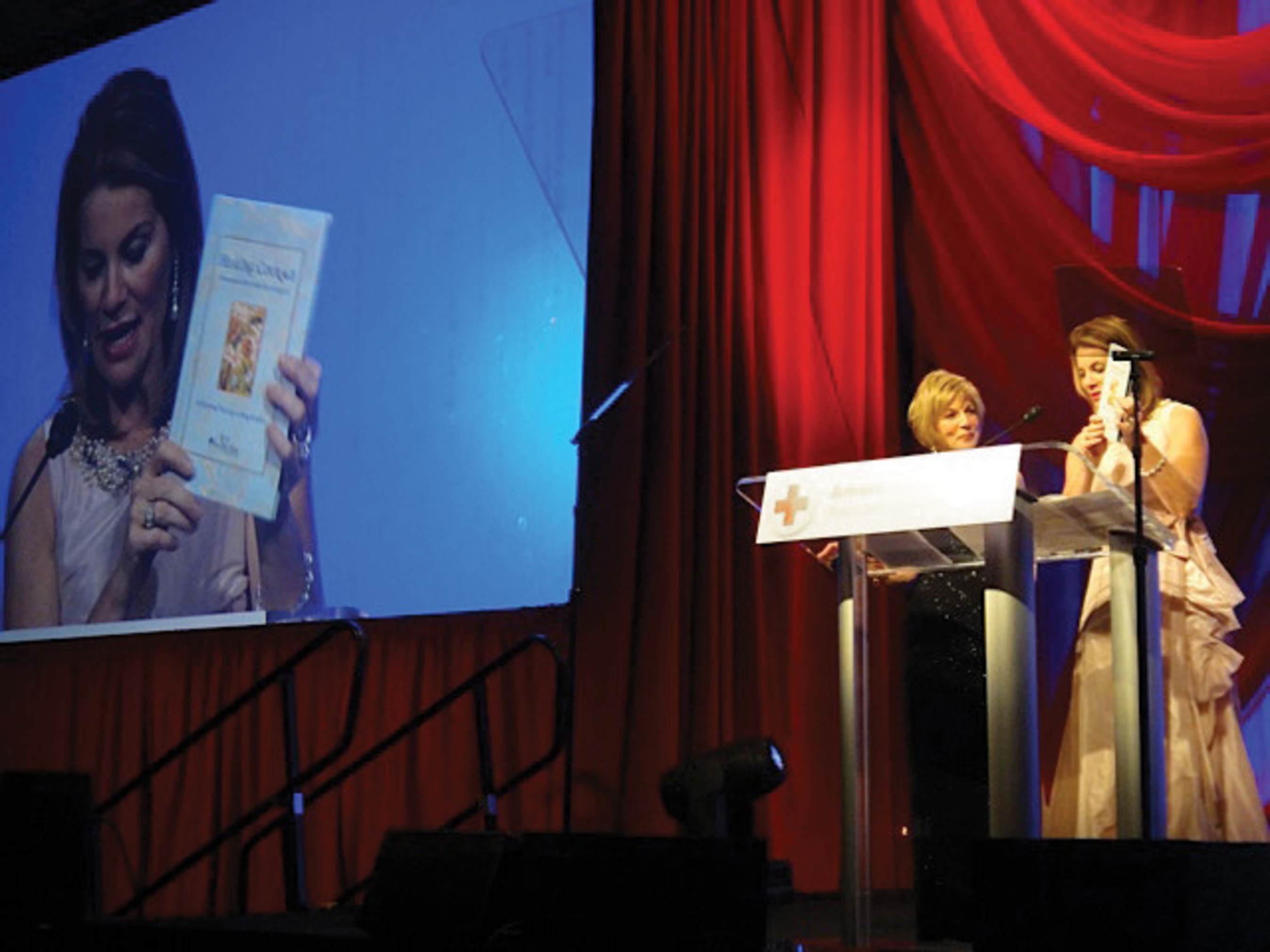 Teresa Carlson, Chairman of the Board of the American Red Cross in the National Capital Region, presenting the Light of Healing Hope Foundation's newest publication, Healing Courage by Alexandra Villard de Borchgrave, at the Red Cross Salute to Service Gala on October 18, 2014. The Light of Healing Hope Foundation offered the book as gifts to the event to support the Red Cross and all Service Members and their families.