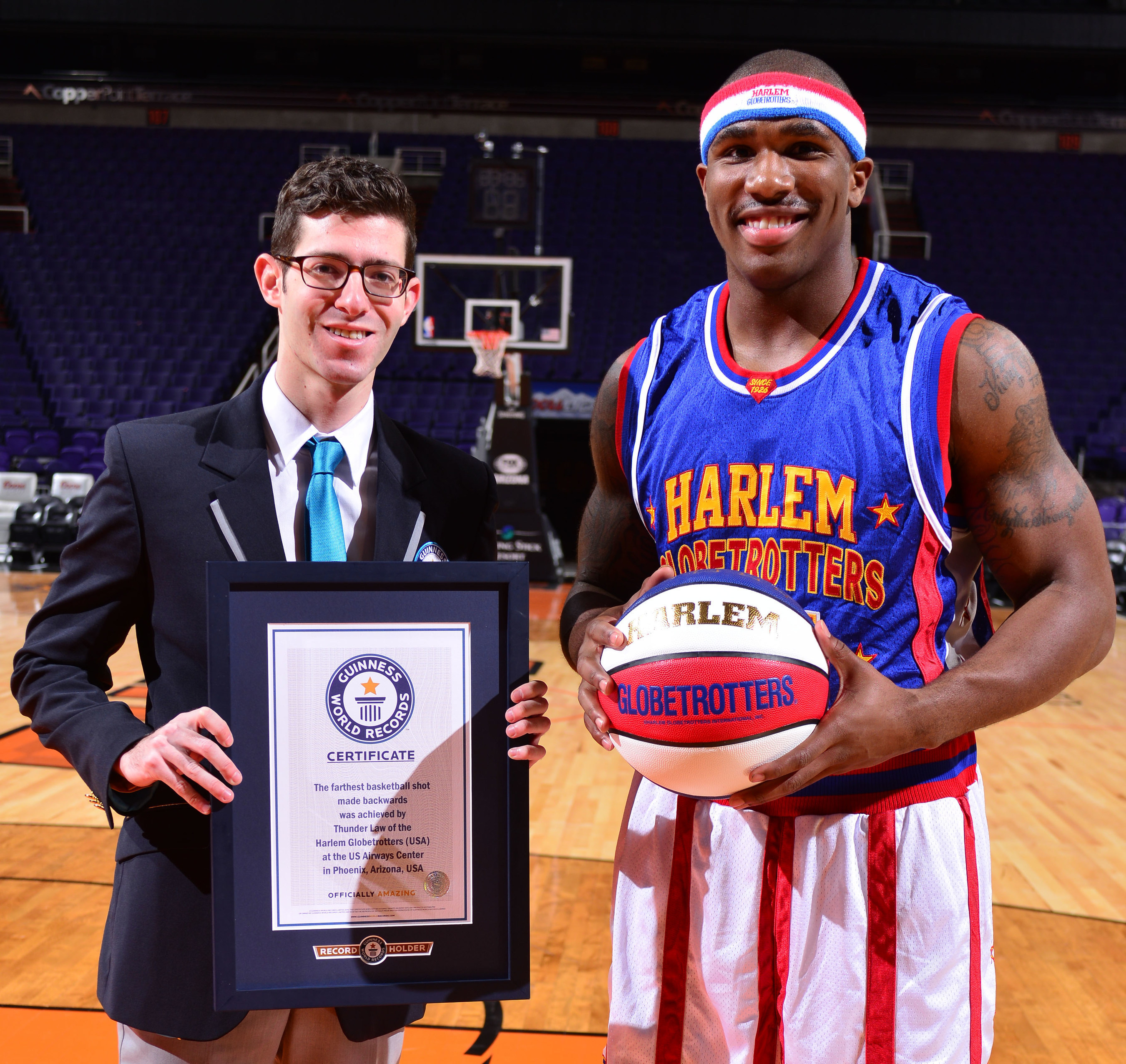 Harlem Globetrotter Thunder Law receives a certificate from Guinness World Records for the  Farthest Basketball Shot Made Backwards - 82 feet 2 inches - in celebration of Guinness World Records Day.