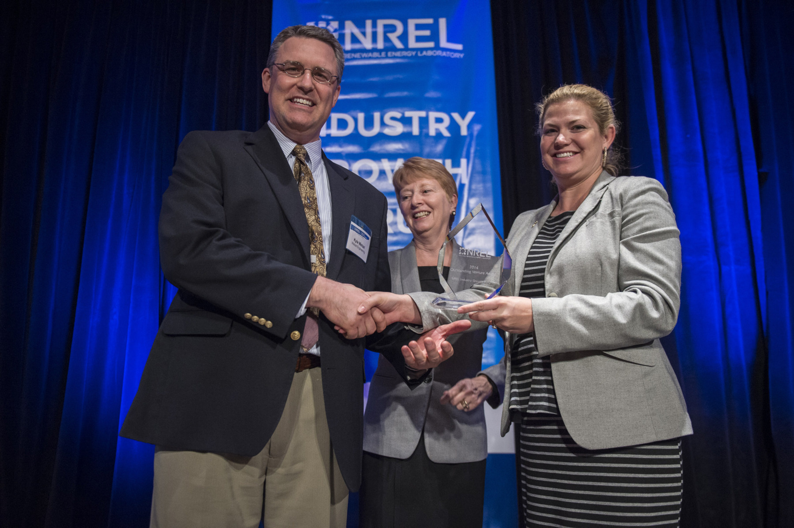 Kyle Wetzel, CTO/Founder of Wetzel Blade receives the Outstanding Venture award for from Bobi Garrett, NREL, and Ashley Grosh, Wells Fargo, at the NREL Industry Growth Forum. The Pflugerville, TX, startup has developed an innovative, field-assembled, component-based wind turbine blade. (Photo by DENNIS SCHROEDER/NREL)