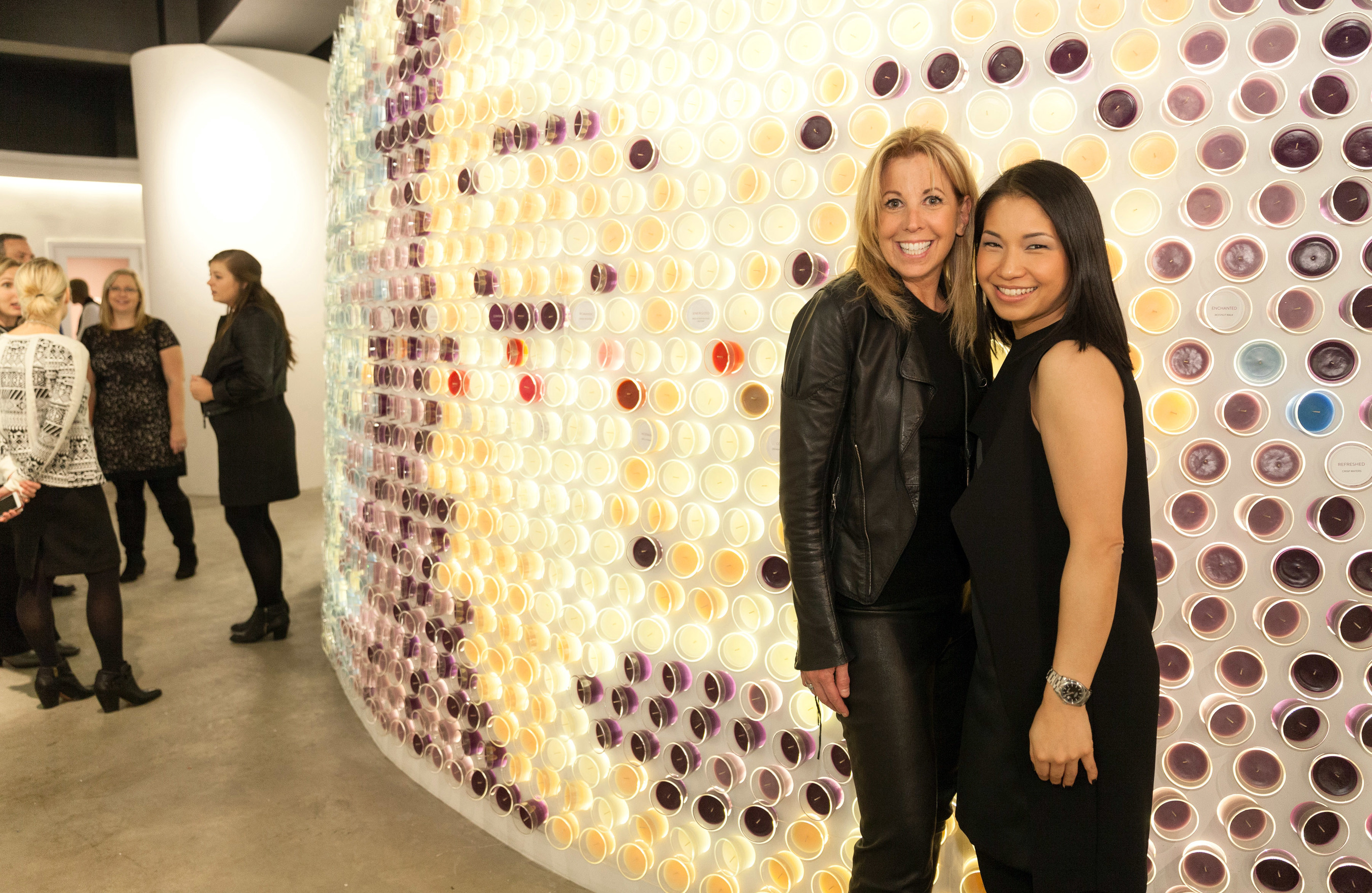 Celebrity fashion designer Pamela Dennis, left, and New York-based designer and architect Stephanie Goto celebrate the grand opening of the Glade(R) Boutique in front of Goto's scent-inspired creation compiled of nearly 1,500 candles in 18 Glade(R) scents Monday, Nov. 17, 2014 in New York.