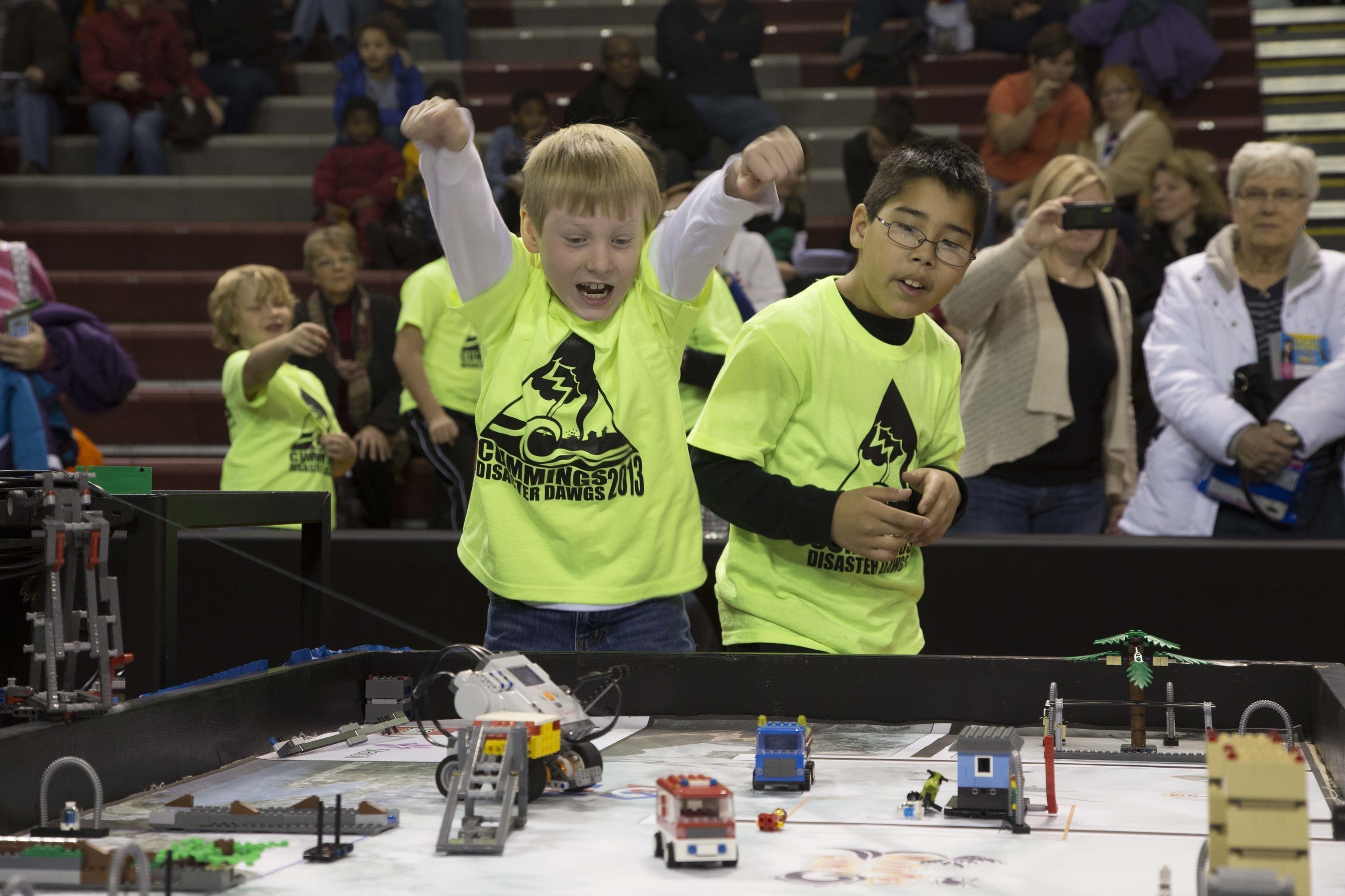 Elementary students from the "Peanut Butter" team prepare their robot for a competition run.