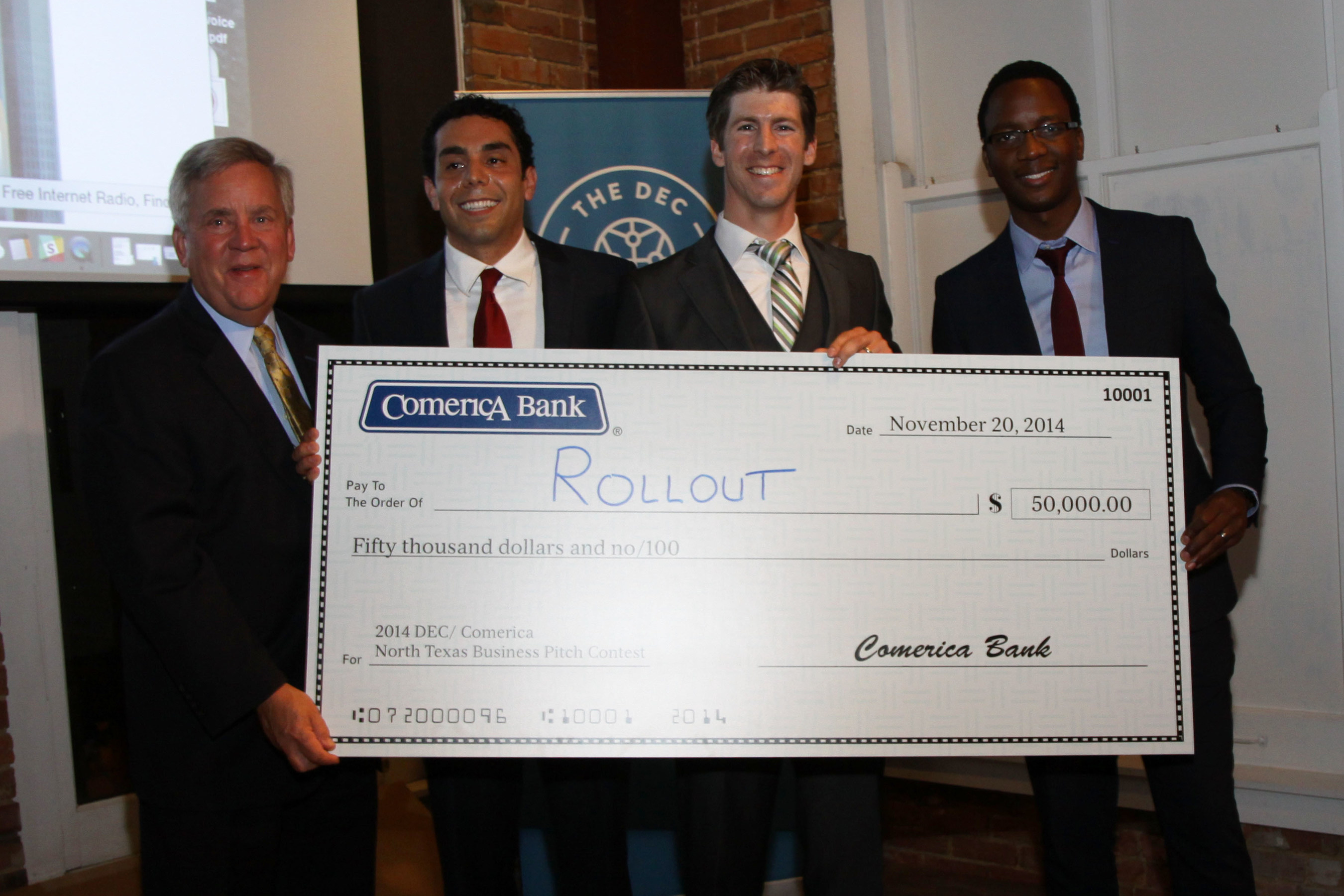 Pat Faubion, Texas Market President for Comerica Bank (far left), presents the $50,000 check to Rollout, Inc., winner of the inaugural DEC/ Comerica North Texas Business Pitch Contest at the Dallas Entrepreneur Center on Thursday evening, November 20, 2014. Rollout execs (from left to right) are Alejandro Jacobo, co-founder & CMO; Matt Hinson, founder & CEO; and Trevor Marimira, product development lead.