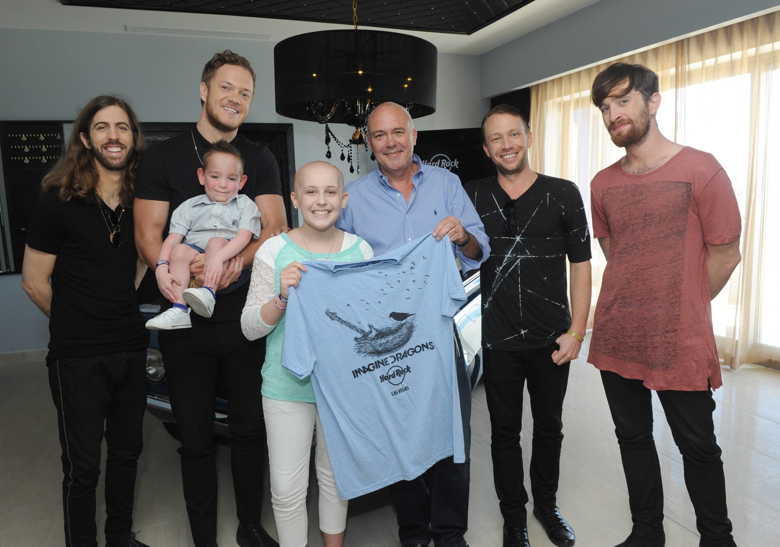 Hamish Dodds, center, President and CEO of Hard Rock International, and Wayne Sermon, Dan Reynolds, Ben McKee and Daniel Platzman, left to right, of Imagine Dragons, meet with Christian Smith, 4, of Dewey, Okla., and Kate Pierson, 13, of West Jordan, Utah, who have benefitted from the Tyler Robinson Foundation, at Hard Rock Hotel Riviera Maya in Mexico, Tuesday, Jan. 20, 2015, as part of the launch of Hard Rock's Imagine Dragons Signature Series T-shirt and pin. A portion of the retail price from sales of the merchandise will benefit the foundation supporting families affected by pediatric cancer. (Photo by Diane Bondareff/Invision for Hard Rock International/AP Images)
