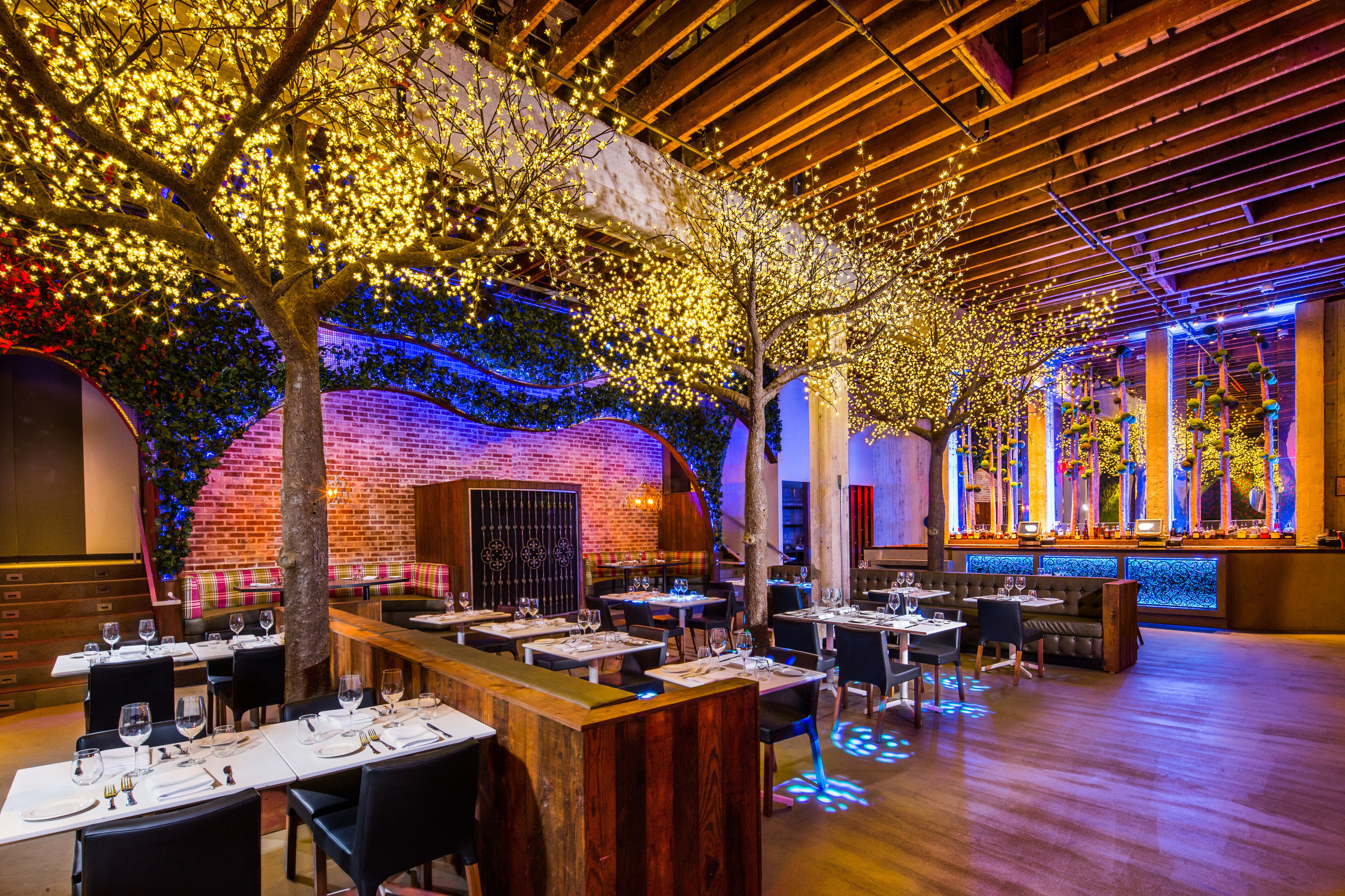 Interior of the newly designed Parq Restaurant, from world-renowned interior design firm Davis Ink., features a mix of raw, organic elements like reclaimed wood, custom yucca trees, and various types of greenery with industrial materials like concrete, aged brick, and metal mesh.