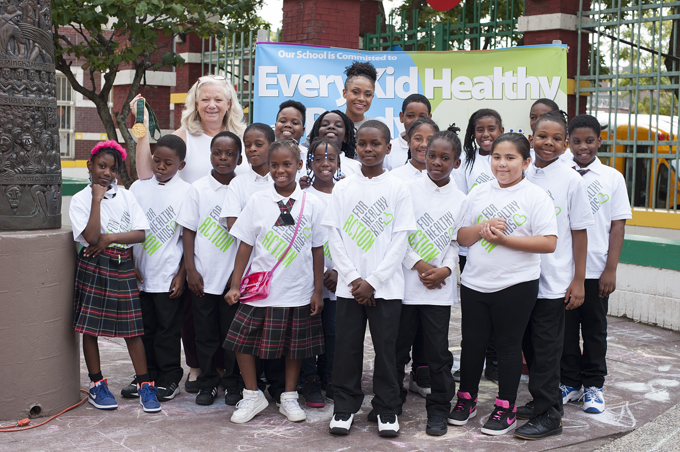Dominique Dawes, Olympic Gold Medalist and GoGo squeeZ Goodness Ambassador, is all smiles with students at P.S. 6 in Brooklyn, NY after leading a workout and announcing a grant to improve access to healthy foods and fitness on behalf of GoGo squeeZ and Action for Healthy Kids on September 21, 2016. (Photo by Phillip Reed).