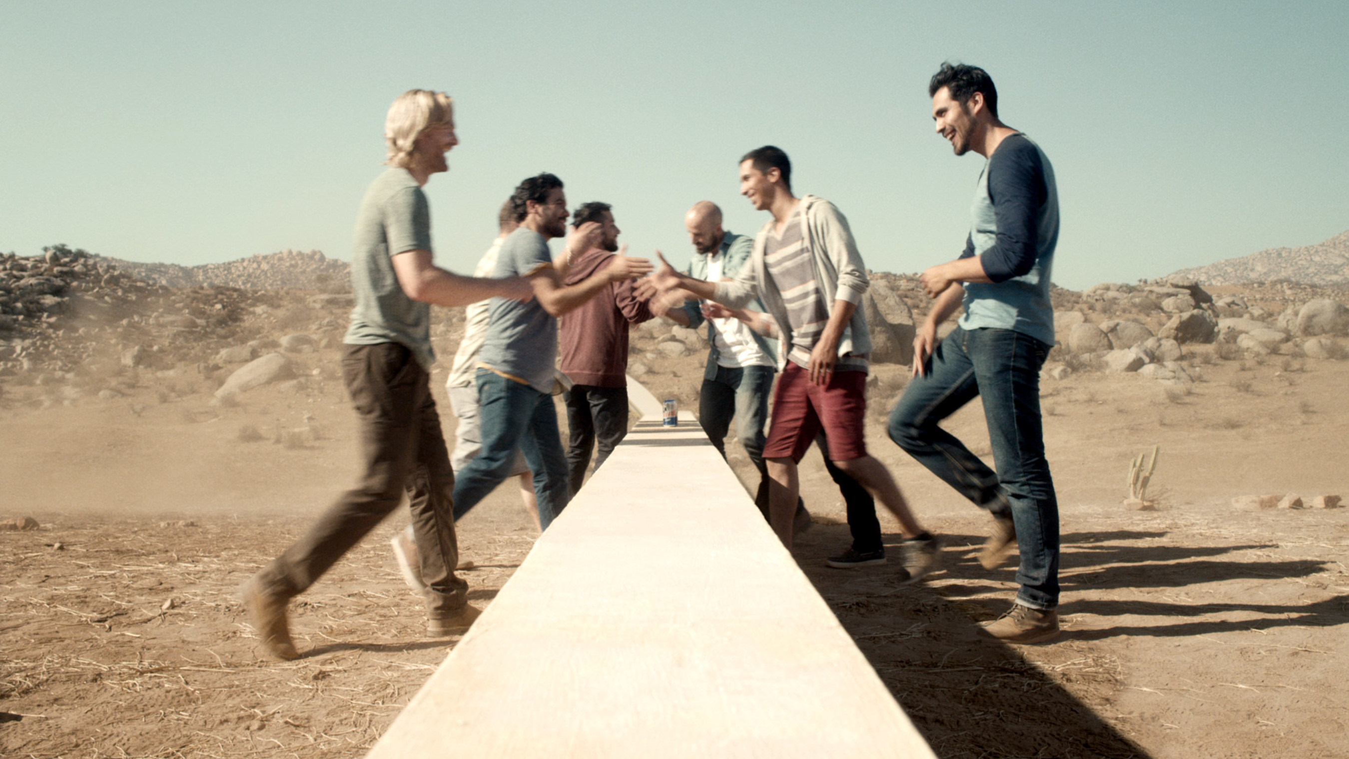 Two groups of young men, bi-cultural Hispanics from the U.S. and Mexicans from Mexico, come together over the wall, the structure is revealed to be three-feet tall, the perfect height for a group of friends to rest their Tecate's on.