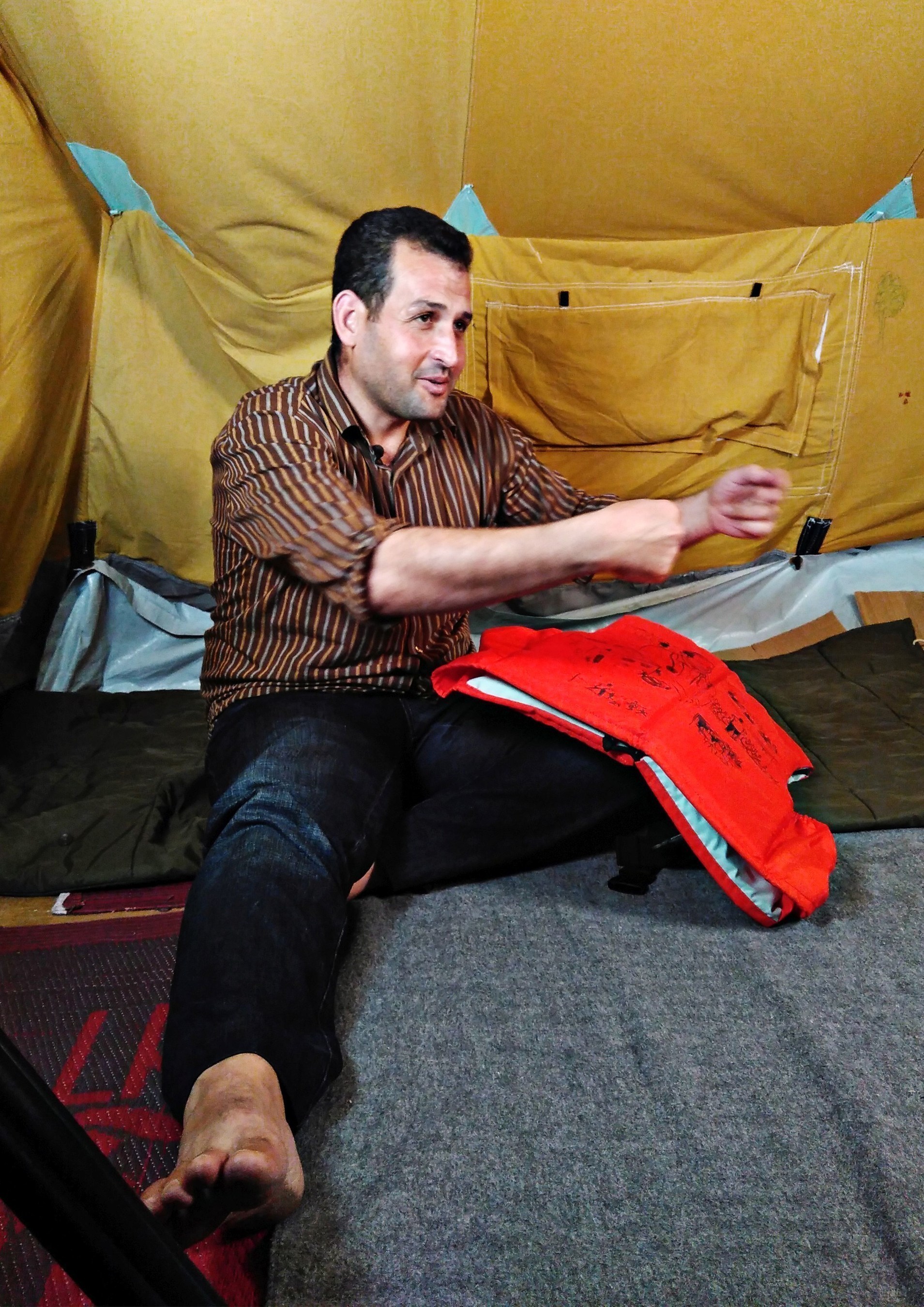 The 29 year old vet Farooq Saadi from Qamishli in Syria conversing in his tent in the "Oreokastro" refugee camp in Thessaloniki, Greece. On his knee is the life jacket bearing his life story. In October 2016, as part of "Project Life Jacket", the life stories of nine Syrian refugees were illustrated on life jackets used for the crossing to Lesbos.
Picture taken on the 7th October 2016 in Thessaloniki. (Project Life Jacket). (PRNewsFoto/Project Life Jacket)