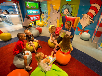 A Camp Ocean counselor reads a Dr. Seuss book to youngsters in the Carnival Freedom's Dr. Seuss Bookville facility -- a unique and dedicated Seuss-themed play space featuring iconic decor, colors, shapes and funky furniture inspired by the whimsical world of Dr. Seuss. (Andy Newman/Carnival Cruise Lines)