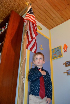 Aaron Howson stands in his bedroom, saluting the American flag.