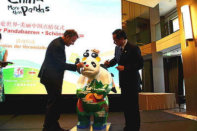 Li Jinzao, chairman of the China National Tourism Administration, and Jochen Szech, president of the Alliance of Independent Travel Traders, added the finishing touches to the eyes of the panda serving as the mascot to the event.