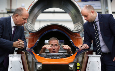 Driver Andy Green sits in the cockpit of Bloodhound SSC as he explains the controls to Frank Klaas, Director of International Communications for Zhejiang Geely Holding Group (ZGH), (left) and Ash Sutcliffe, (right) PR Manager for ZGH.