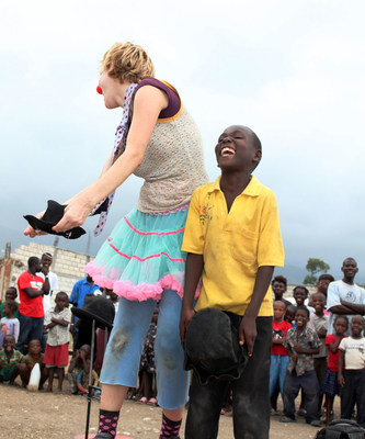 A laughing young boy joins a clown who is performing for a large crowd in Haiti. This project supported earthquake relief.