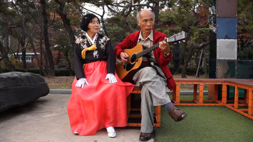 A scene from the movie. An old lady is singing a song in accordance with guitar playing.  (PRNewsFoto/Seoul Metropolitan Government)
