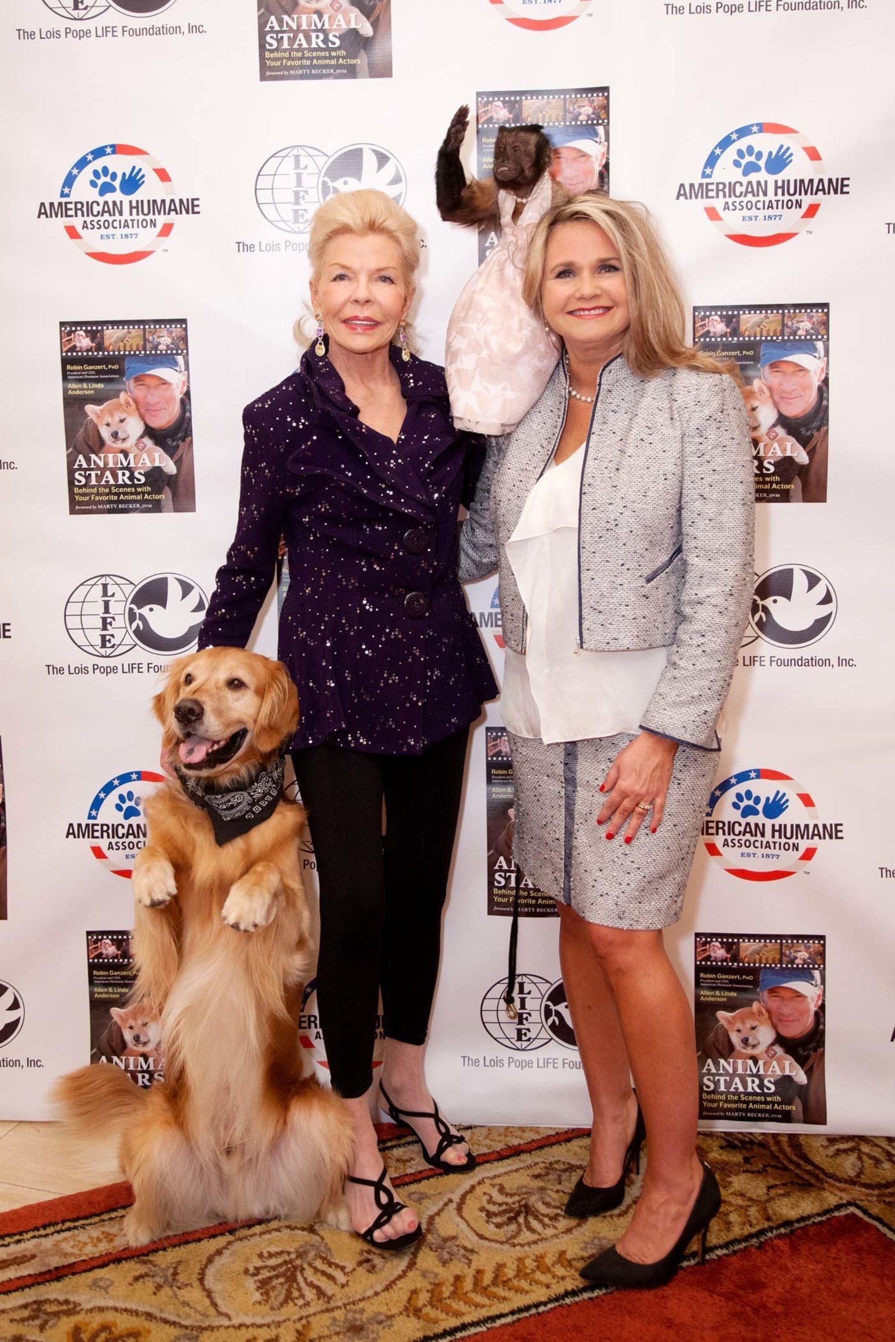 Philanthropist Lois Pope (left) and American Humane Association president and CEO Dr. Robin Ganzert pose with animal actors Hudson the Golden Retriever and Crystal the Capuchin at American Humane Association's "Afternoon Tea with Animal Stars" event sponsored by Mrs. Pope in Palm Beach, Florida on Thursday January 22nd.Crystal and Hudson were the two featured guests at the inspiring event, educating a crowd of animal and movie lovers alike about the hard work of animal actors and their trainers and what it takes to protect them on set.