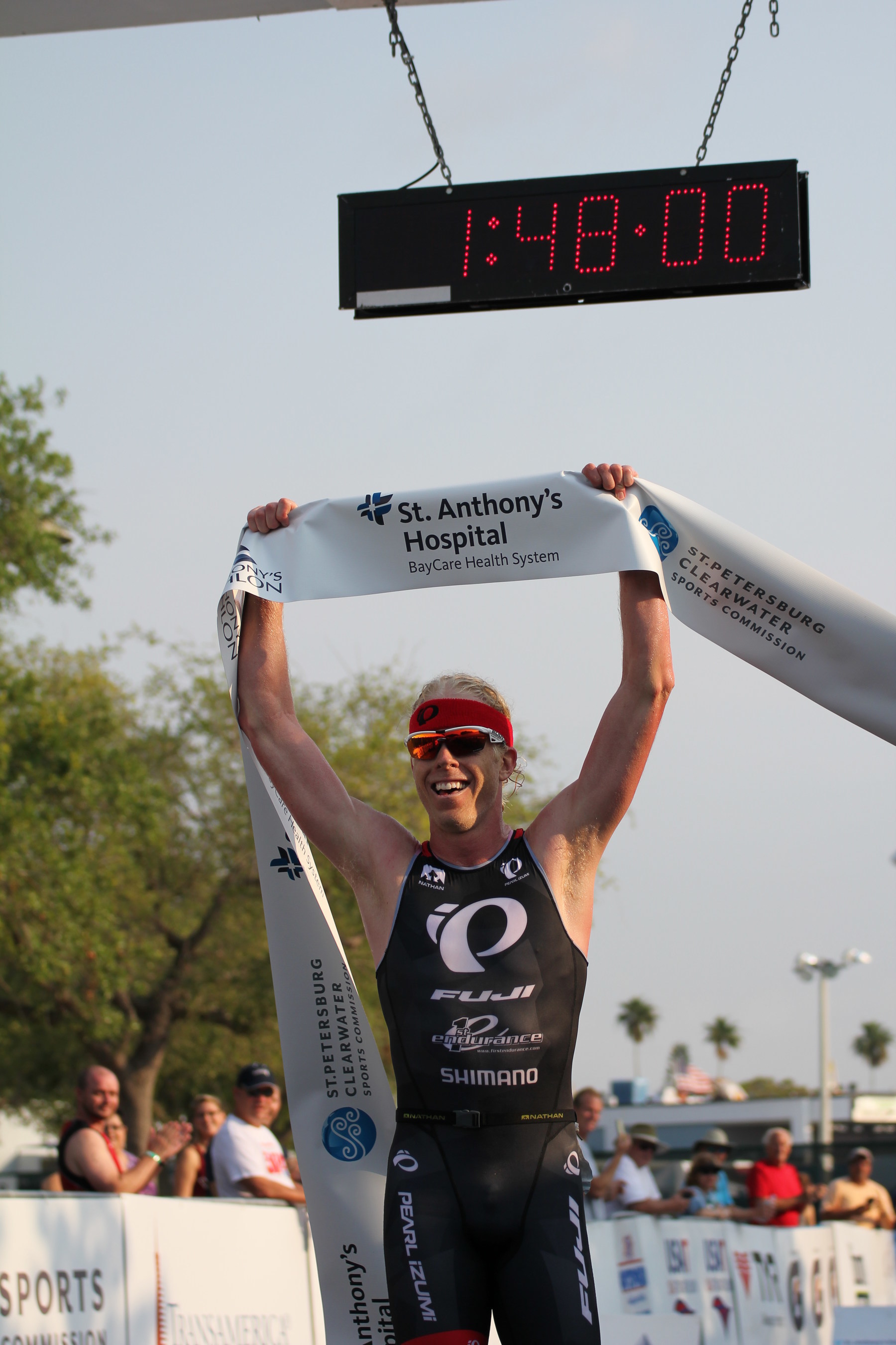 Cameron Dye crosses the finish line first at the St. Anthony's Triathlon