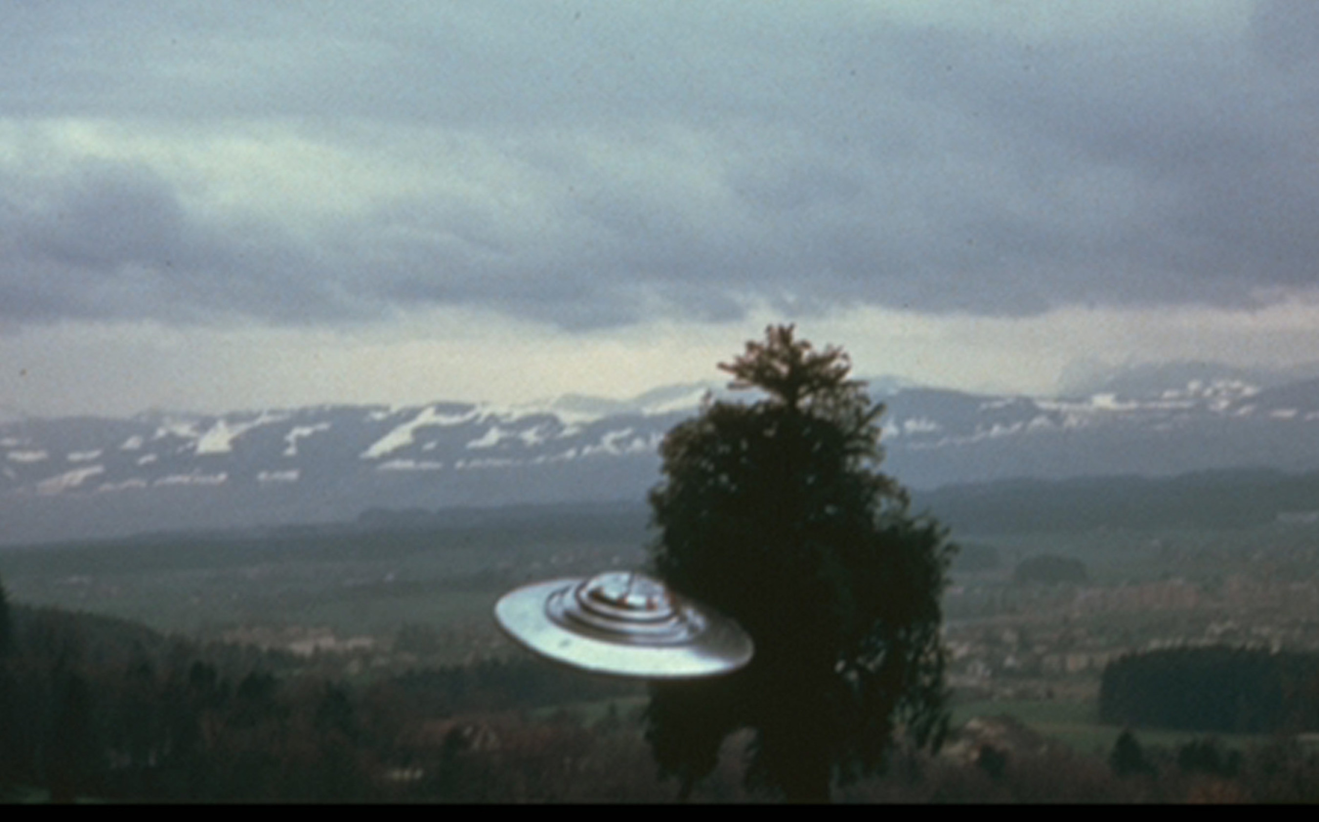 UFO photo by Billy Meier, July 9, 1975, Switzerland. One of nine showing UFO circling the tree. Meier took 1,200 clear, daytime photos on 35 mm film, pre-computer, pre-digital era. Independent, expert analysis showed no models, miniatures or special effects, with real, full-sized tree. Meier took eight films, a video,  sound recordings and presented metal samples for analysis. All of his evidence remains irreproducible. His contacts with the Plejaren extraterrestrials began in 1942...and continue today. Purpose is to help us assure our own future survival. His prophetic information warned of WTC attack, terrorism, wars, Ebola and AIDS epidemics, etc.