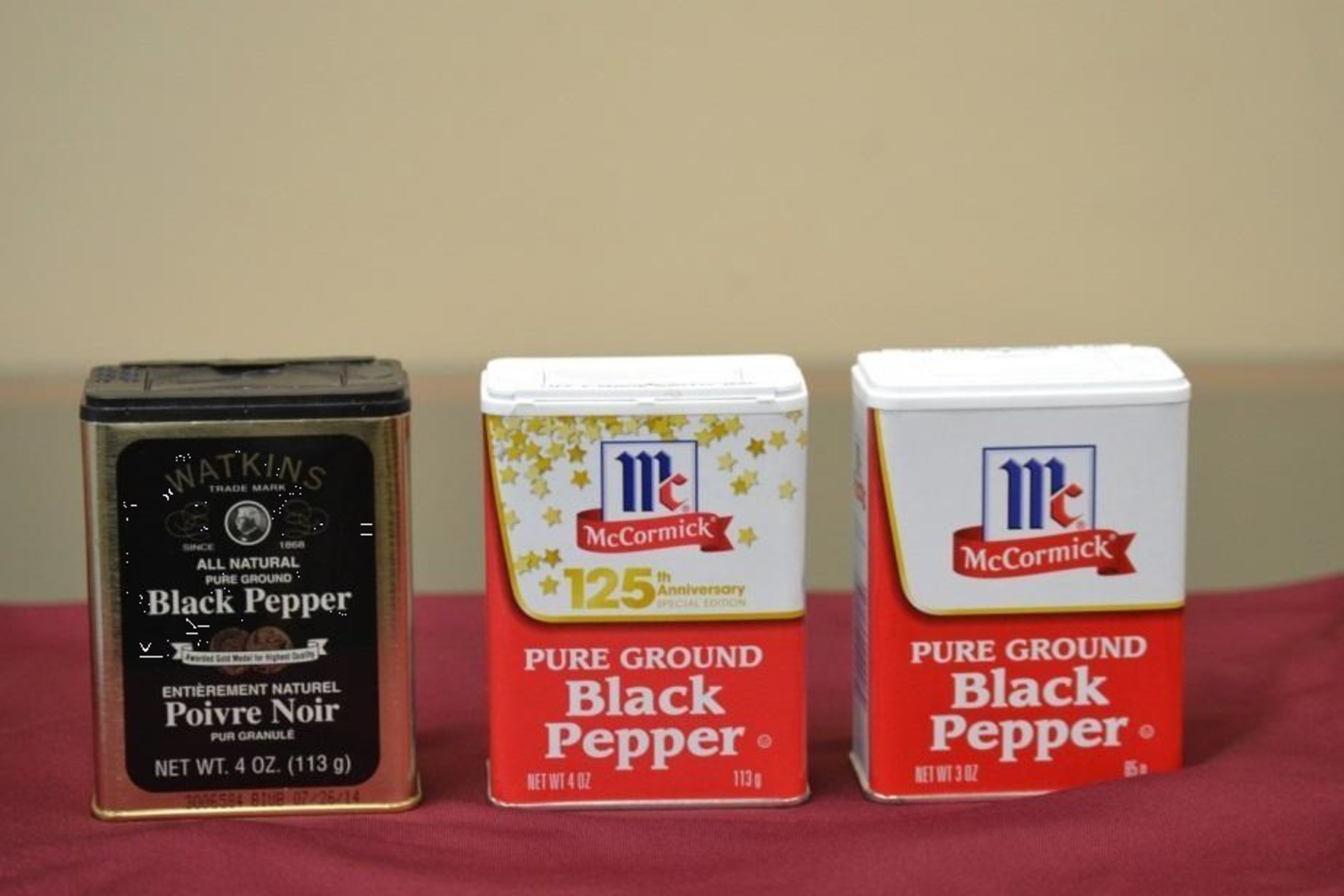 Photo showing Watkins tin with 4-ounce fill along with traditional McCormick Medium Tins with traditional 4-ounce fill and 3-ounce slack-fill.