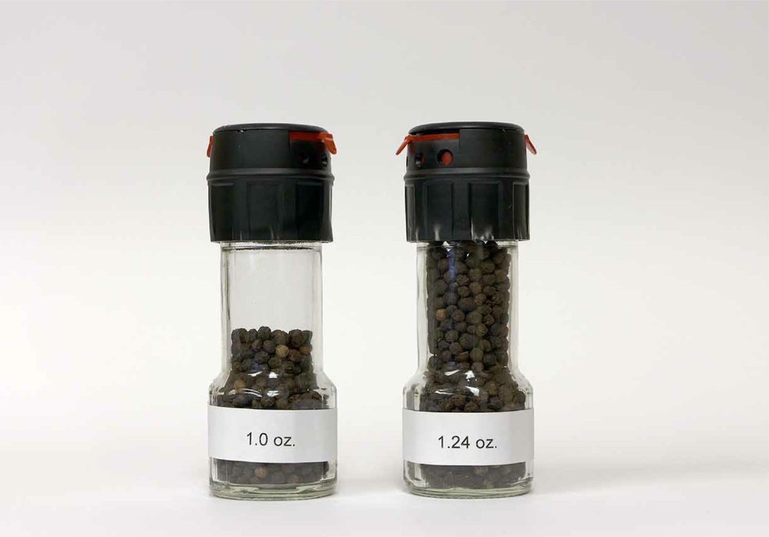 Exhibit A: Photo of the original 1.24 oz. McCormick black peppercorn grinder and the now 20% content reduced-size ("slack filled") 1 oz. McCormick black peppercorn grinder. These bottles were opened to confirm weight.