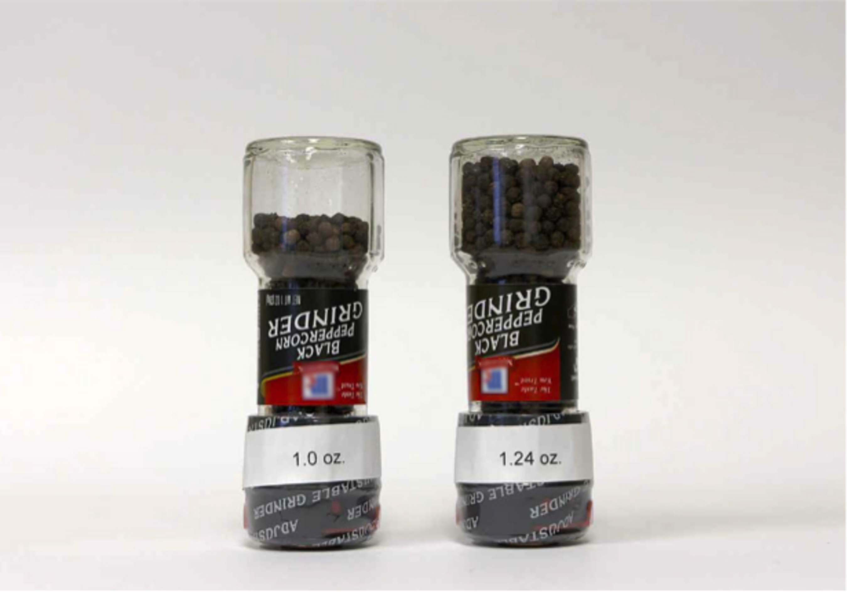 Exhibit C: Photo of the original 1.24 oz. McCormick black peppercorn grinder with full label and the now 20% reduced-size ("slack filled") 1 oz. McCormick black peppercorn grinder with full label in sealed bottles upside down to show "slack fill".