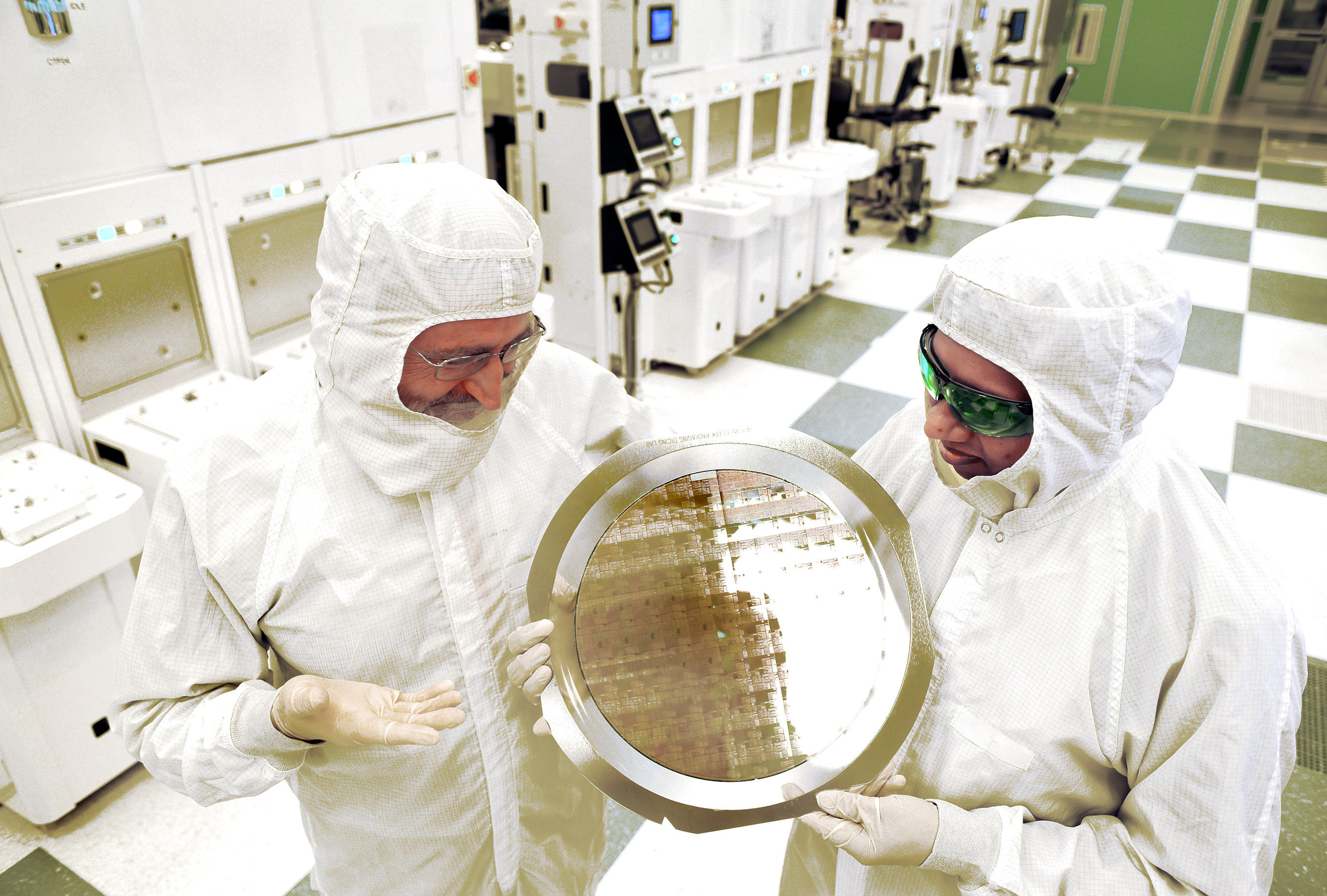 An alliance led by IBM Research has produced the semiconductor industry's first 7nm (nanometer) node test chips with functional transistors. The breakthrough, accomplished at SUNY Polytechnic Institute's Colleges of Nanoscale Science and Engineering (SUNY Poly CNSE), could result in the ability to place more than 20 billion tiny switches -- transistors -- on the fingernail-sized chips that power everything from smartphones to spacecraft. Dr. Michael Liehr (left) of SUNY Poly CNSE and Bala Haran (right) of IBM Research inspect a wafer comprised of 7nm (nanometer) node test chips in a clean room in Albany, NY.