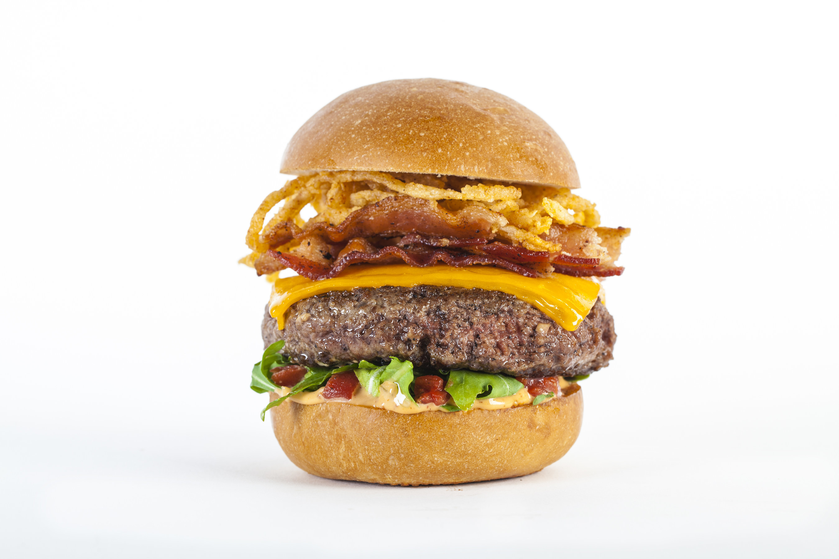 Burger Parlor Smokey Burger - Hormone free and antibiotic free Nebraskan beef is ground fresh in house and topped with smoked bacon, crispy onions, Wisconsin cheddar cheese, arugula, oven roasted tomatoes and chipotle aioli to create this fan favorite.