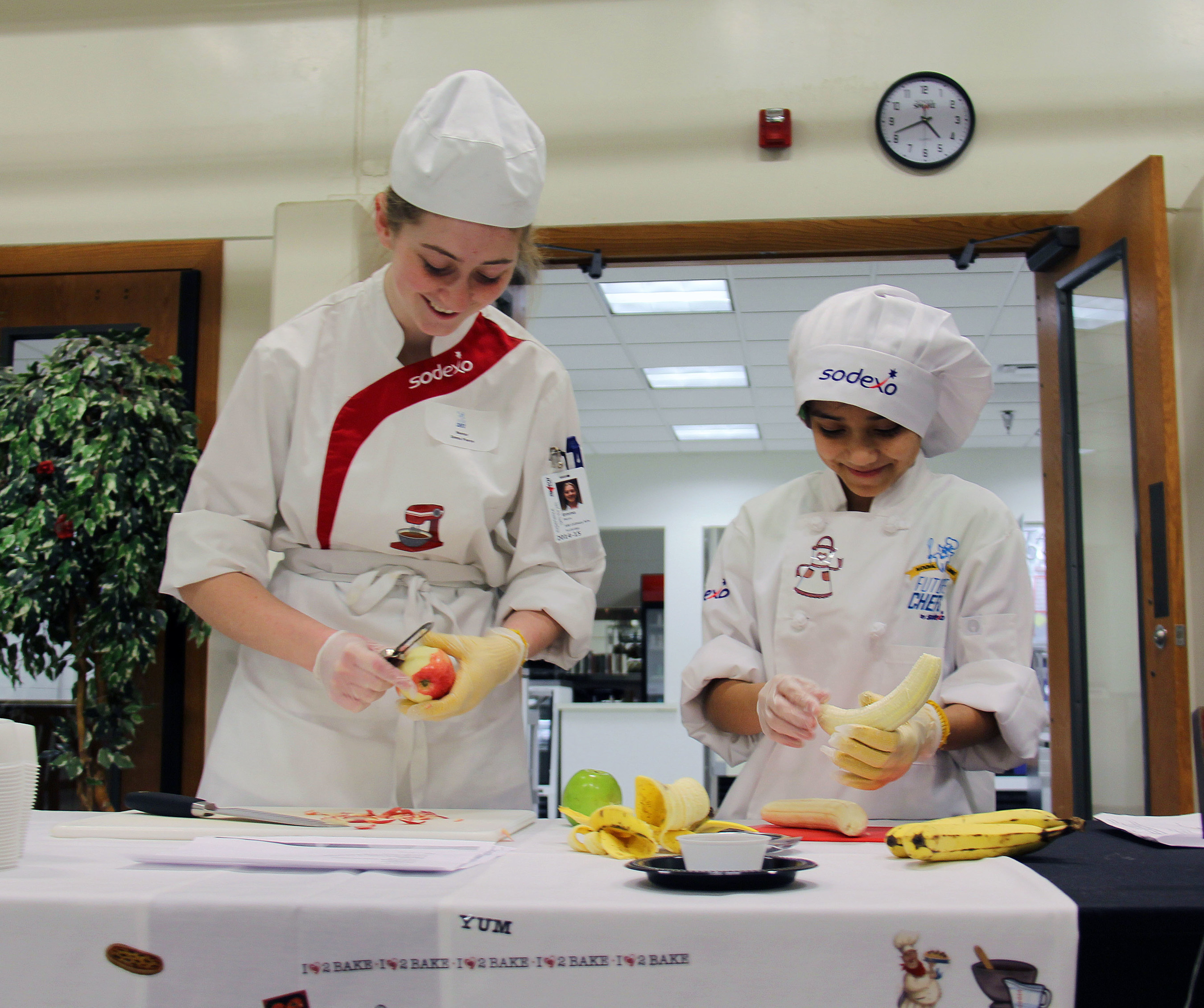 A sodexo chef lends a hand and some culinary guidance to a student at a Sodexo Future Chefs event.