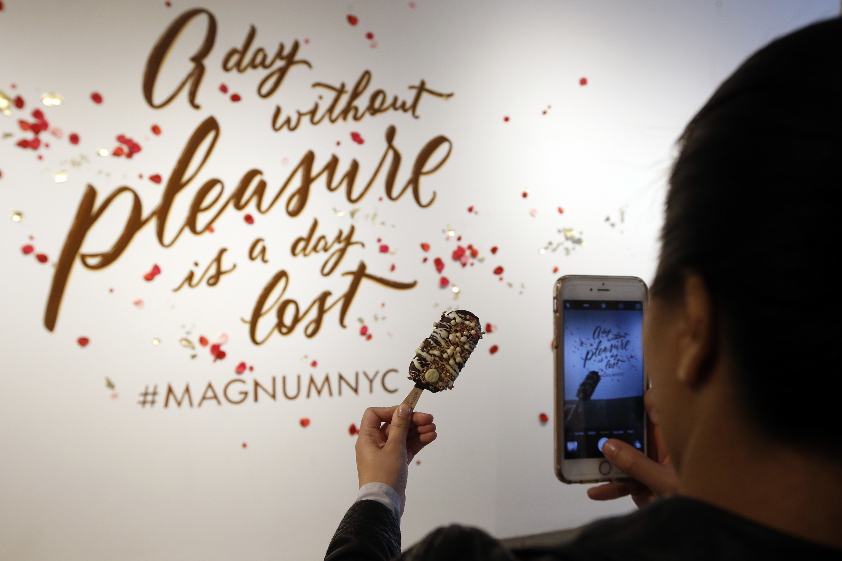 A guest at MAGNUM New York captures a close-up photo of a custom MAGNUM Ice Cream bar. At the store's "dipping bar," guests can create custom MAGNUM bars with a selection of decadent ingredients, including rose petals, espresso sugar and gogi berries. This is the first U.S. storefront for MAGNUM Ice Cream and it's located at 134 Prince Street in SoHo; for more information, visit Facebook.com/MAGNUM. (Photo by Jason DeCrow for MAGNUM)