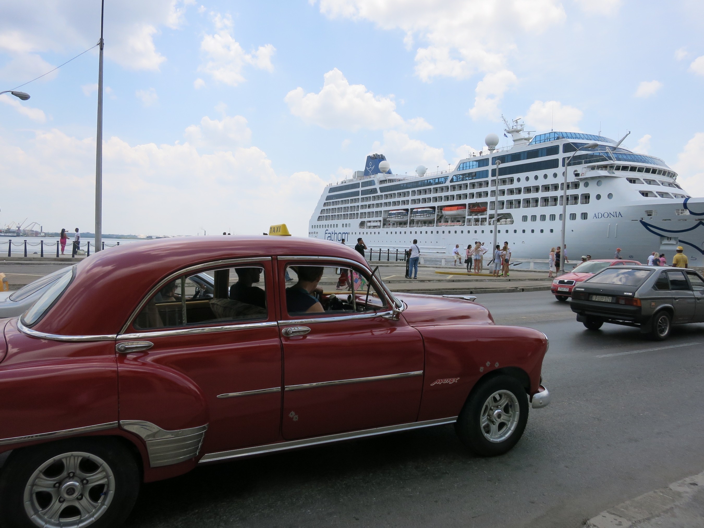A classic American car serving as a taxi in Havana drives past Carnival Corporation's Fathom Adonia cruise ship -- which on May 2 became the first U.S. cruise ship in over 50 years to sail from the U.S. to Cuba.