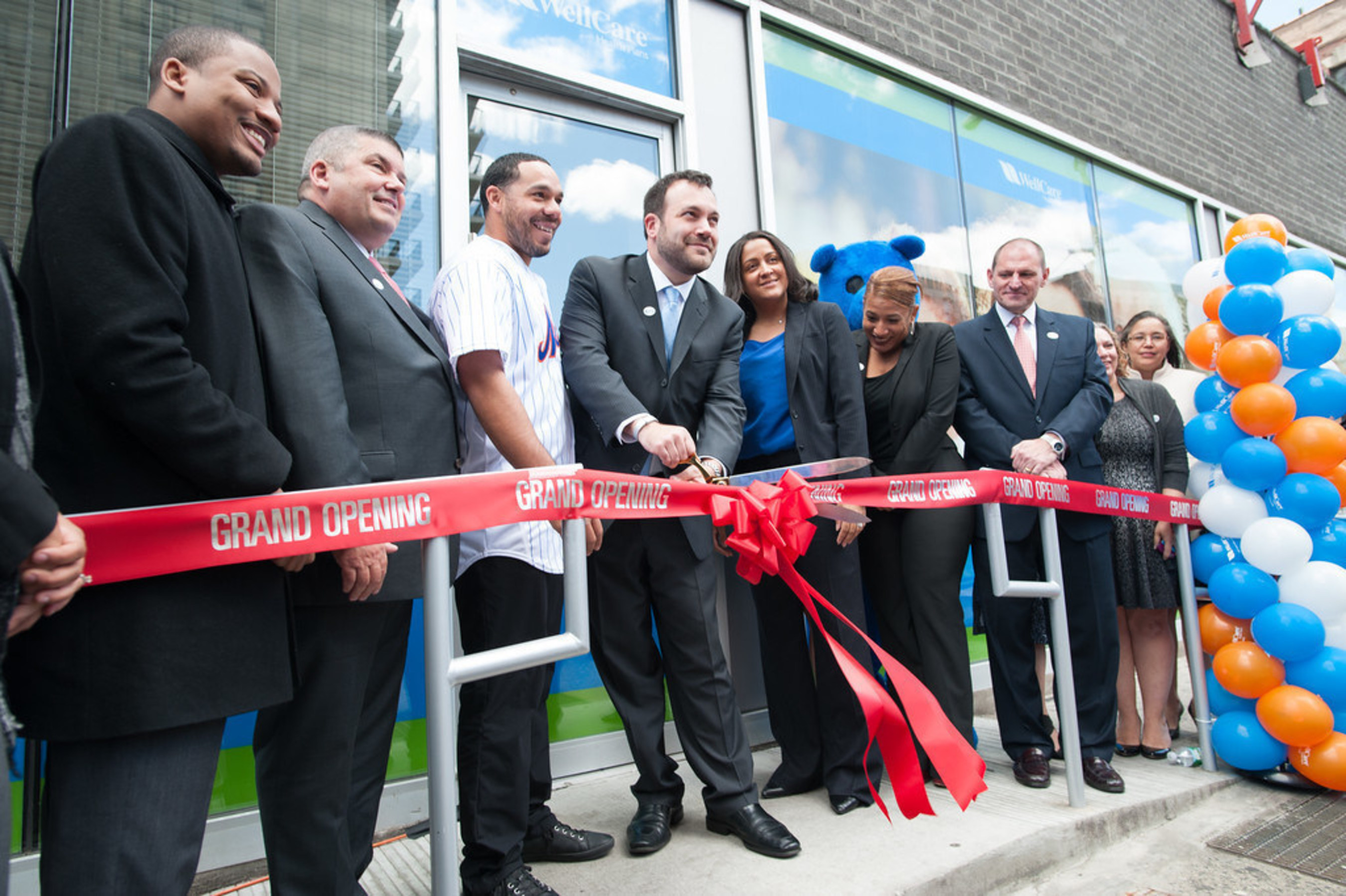 Center with scissors, Ryan Fogarty, WellCare's vice president, New York and Connecticut, cuts the ribbon to WellCare's newest Welcome Center in Manhattan's Washington Heights. To Fogarty's left is New York Mets catcher Rene Rivera, to Fogarty's right is Jeanette Gonzalez, WellCare's senior director of provider relations. WellCare Welcome Centers are neighborhood health information, education and activity centers.
