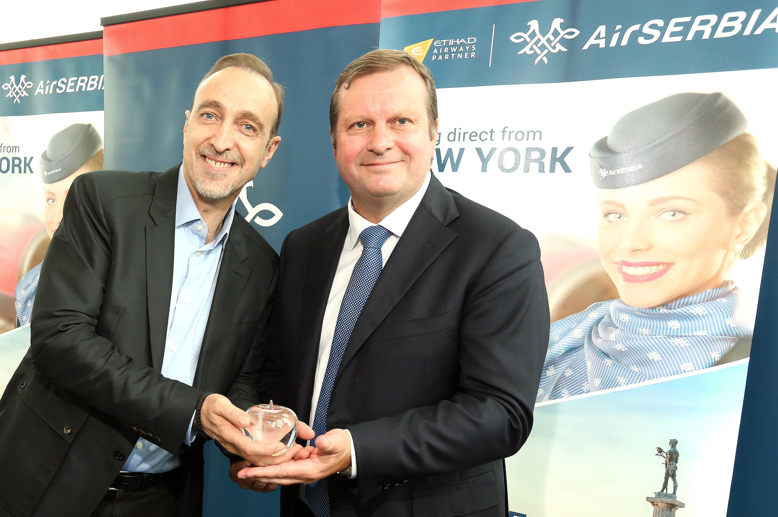 Gert-Jan de Graaf, President and Chief Executive Officer of JFK IAT, LLC presents Dane Kondić, Chief Executive Officer of Air Serbia with a commemorative glass apple to celebrate the start of Air Serbia's non-stop service from Belgrade to New York.