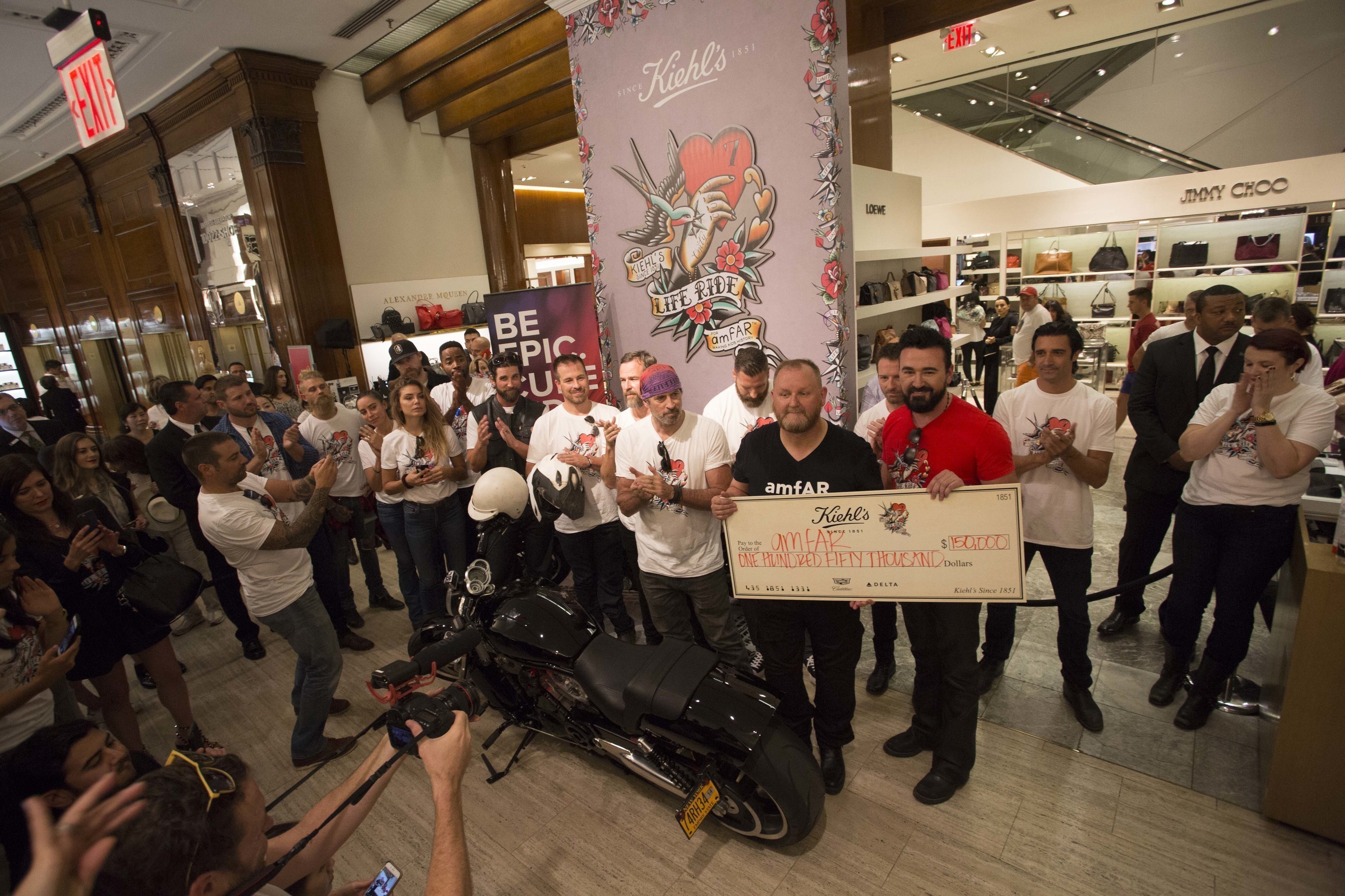 Kevin Robert Frost, CEO of amfAR, The Foundation for AIDS Research, accepts a $150,000 check from Chris Salgardo, President of Kiehl's Since 1851 during Kiehl's LifeRide for amfAR, an annual charity motorcycle ride that took place Aug. 3 through Aug. 13, 2016. Kiehl's and amfAR have announced that the $150,000 raised at this year's Kiehl's LifeRide for amfAR will go toward a specific cure-focused research project led by Satish Pillai, Ph.D., Associate Investigator at the Blood Systems Research Institute and Associate Professor of Laboratory Medicine at the University of California, San Francisco.