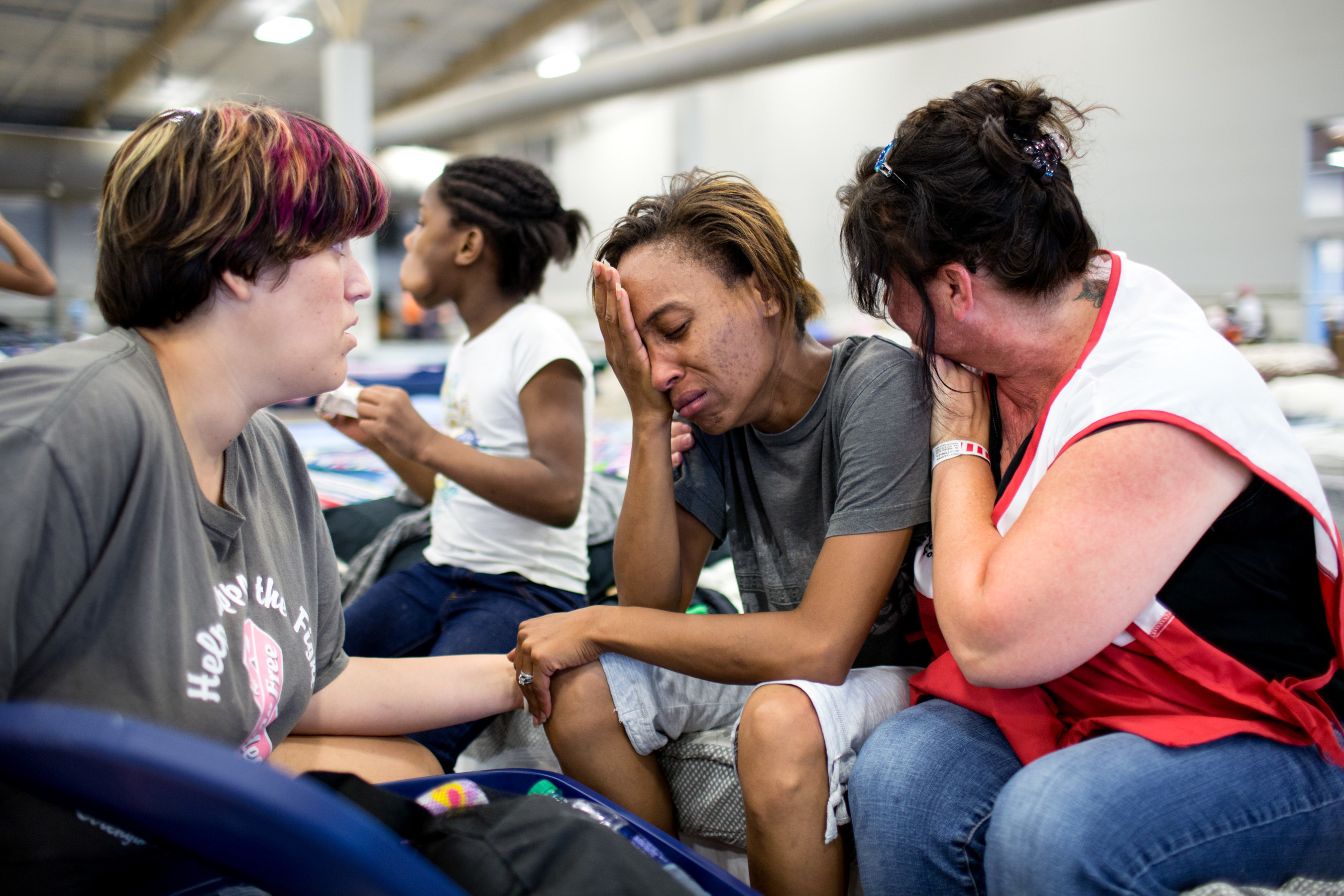 Courtney Robinson (center) is nearly certain that her home is destroyed because of the record flooding in Louisiana. She is staying at a Red Cross shelter with her five children and husband who fled the flood waters with some food and water and a change of clothes for the family. She shared their story with Red Cross relief worker Elizabeth Stander, and Rachel Ambeau, who is also displaced and staying at the Red Cross shelter, in Gonzales, Louisiana. Red Cross Photo by Marko Kokic