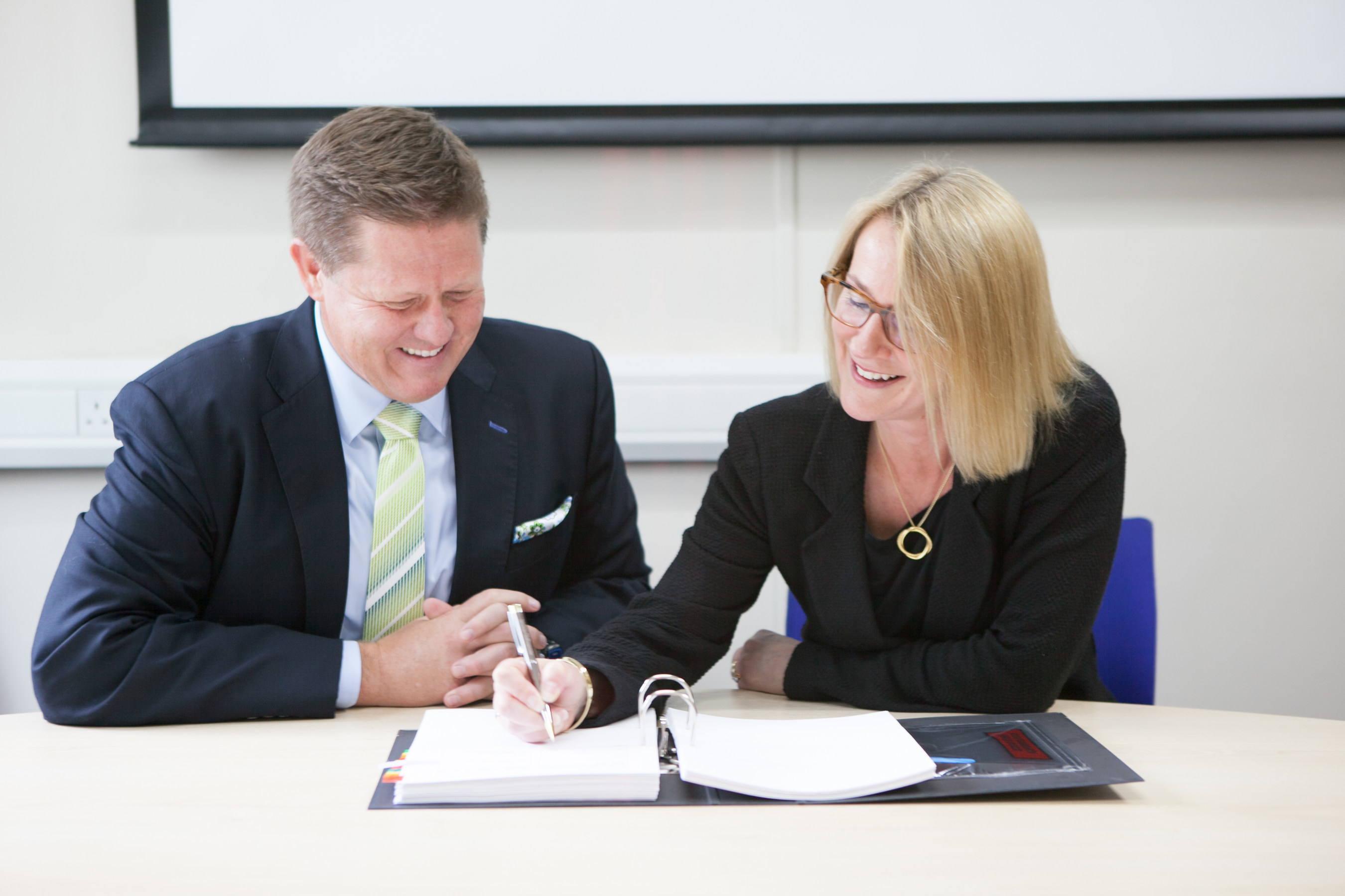 Matthew Hawkins, president of Sunquest Information Systems, signs the contract with Dr. Tracey Batten, chief executive officer of North West London Pathology Consortium.