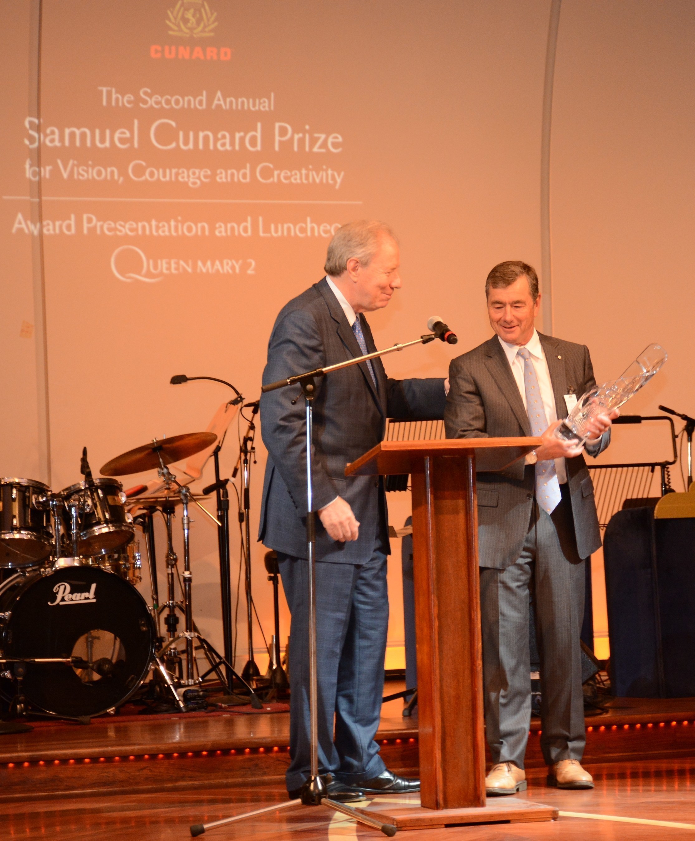 Onboard Cunard's flagship, Queen Mary 2, John Risley, recipient of the Second Annual Samuel Cunard Prize for Vision, Courage and Creativity accepts the award on board from last year's honoree, Jim Irving.