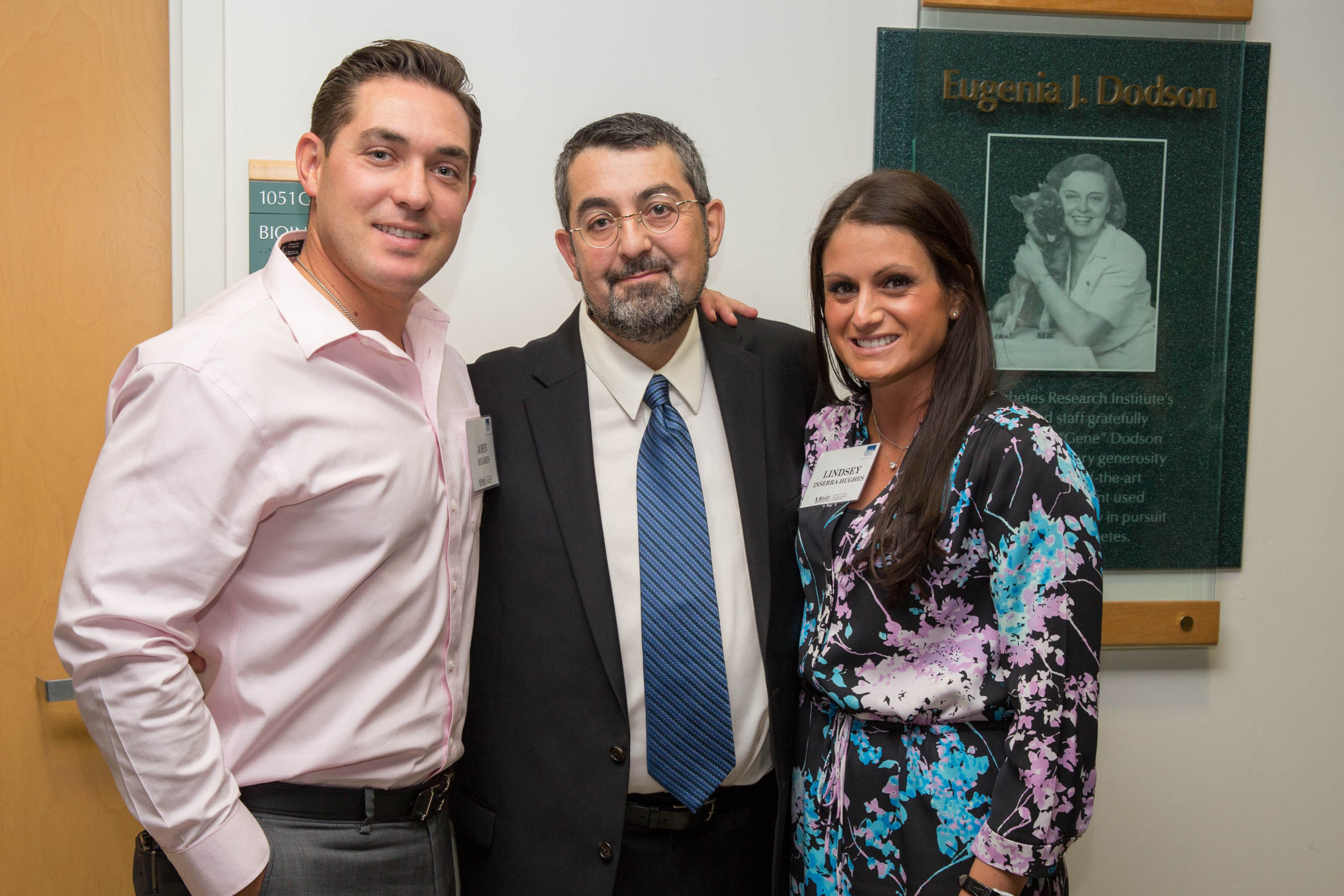 Immune Tolerance Leader Alberto Pugliese, M.D. (center) of the Diabetes Research Institute with John Hughes and Lindsey Inserra-Hughes, in front of a plaque with a photo of the late Eugenia Dodson.  Dr. Pugliese's specialty was highlighted throughout the day during the Lindsey Inserra-Hughes Immune Tolerance Seminar Series and the presentation of the J. Enloe and Eugenia J. Dodson Chair in Diabetes Research, which was held at the Diabetes Research Institute at the University of Miami Leonard M. Miller School of Medicine.