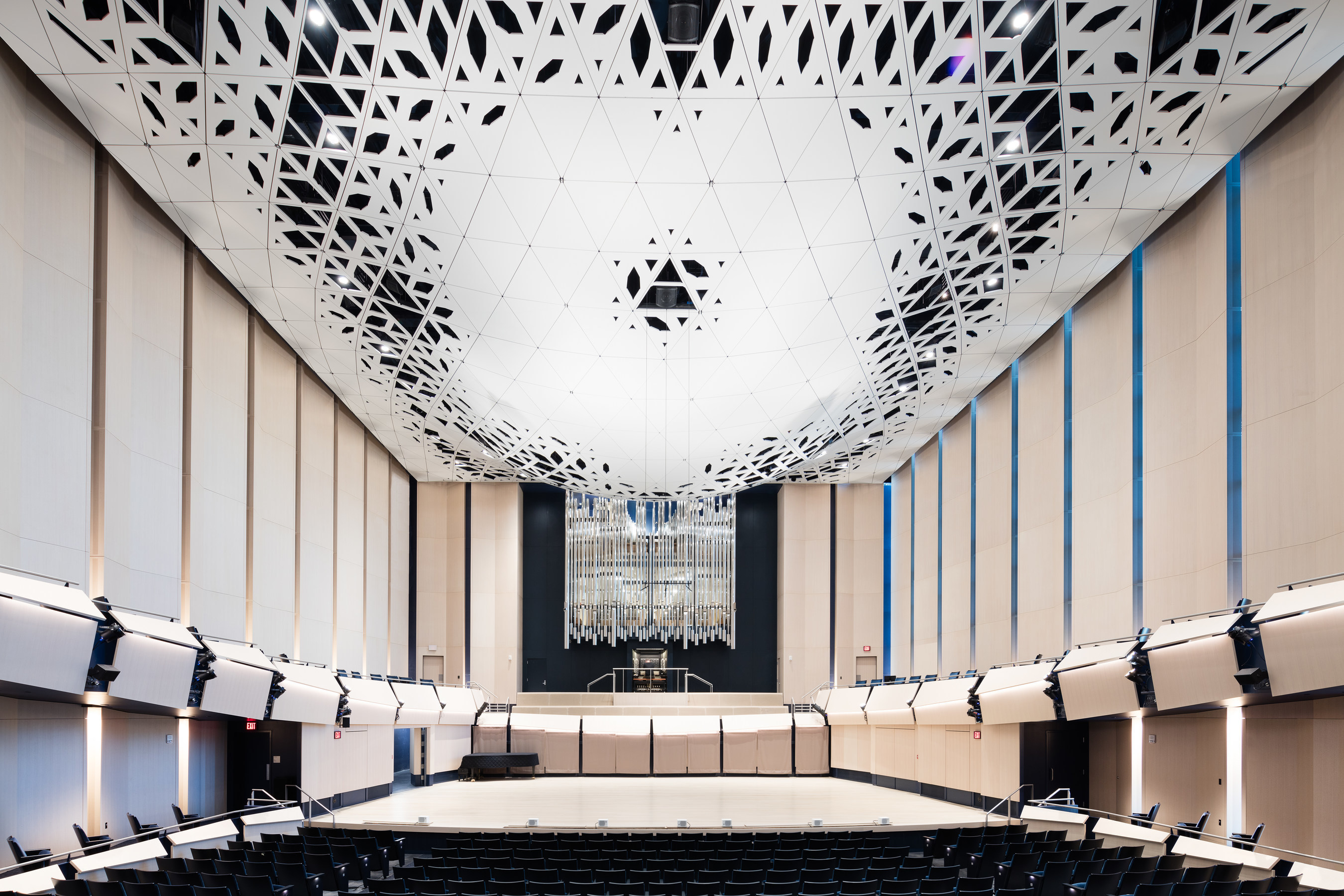 Voxman Music Building, University of Iowa. The 700-seat performance hall features a "theatroacoustic" ceiling system devised to unify acoustics, lighting, and life-safety requirements into a single dramatic, multi-functional architectural expression. The resulting intricately sculpted element is assembled out of 946 unique, folded-aluminum composite modules. Image courtesy LMN Architects.