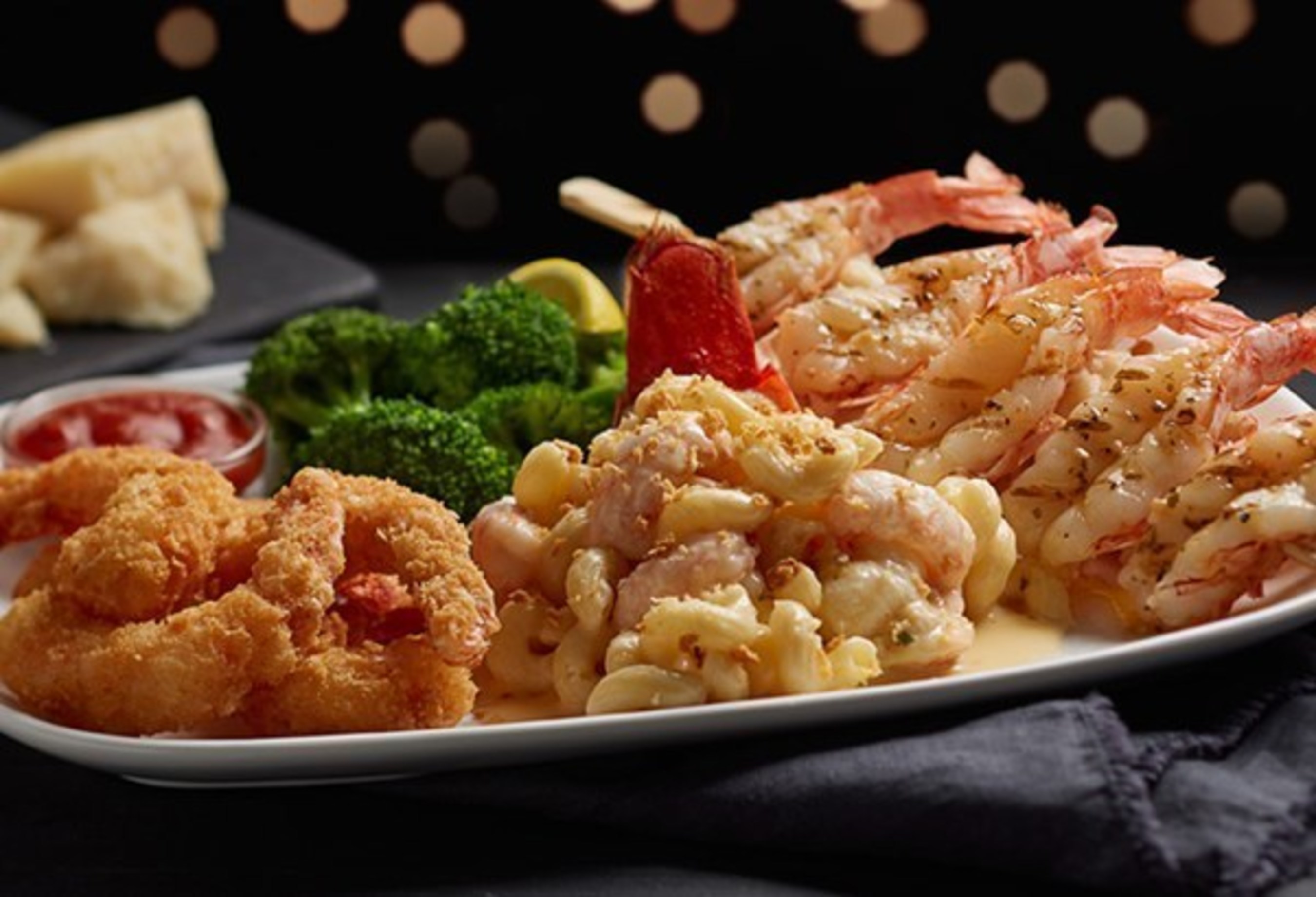 Red Lobster's NEW! Wild-Caught Lobster-and-Shrimp Trio features a wood-grilled Maine lobster tail topped with Norway lobster mac-and-cheese, paired with a garlic-grilled red shrimp skewer and panko-crusted red shrimp with Red Lobster's classic cocktail sauce.