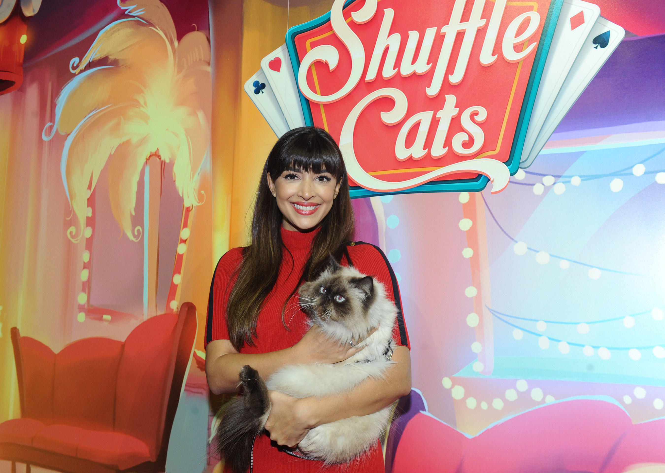 Actress Hannah Simone poses with Wylie Coyote Super Genius, the winner of America's Next Shuffle Cat contest, after a live cat-walk in New York, Tuesday, Dec. 6, 2016.  Wylie will be featured in Shuffle Cats, the new mobile game from King.  (Photo by Diane Bondareff/Invision for King/ AP Images)