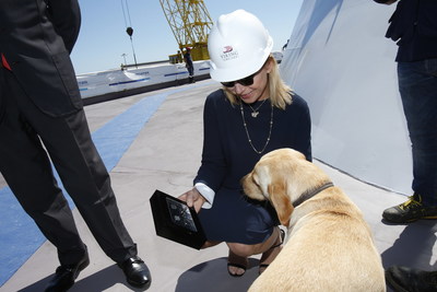 Karine Hagen and her Labrador, Finse, admiring Norwegian commemorative coins before they are welded under the ship's mast. The coins represent  four generations of birth years in her family: 1911 (grandmother Ragnhild, after whom the onboard restaurant Mamsen's is named); 1943 (father Torstein, Viking's chairman); 1970 (Karine's own birth year) and 2012 (Finse).