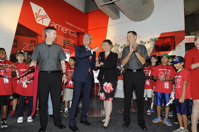 Virgin America COO Steve Forte and Frontiers of Flight Museum President and CEO Cheryl Sutterfield-Jones cutting the ribbon during the  unveiling of the airline's new exhibit at the museum. Virgin America, the airline known or low fares and upscale service, also demonstrated its support for the local community by announcing it will help provide scholarships for students attending the Museum's Flight School and other educational programs.