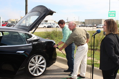 Matthew Budraitis and Don Ketcham, Farley engineers, plug-in an electric vehicle to officially open the charging stations as Farley Site Vice President Cheryl Gayheart looks on.