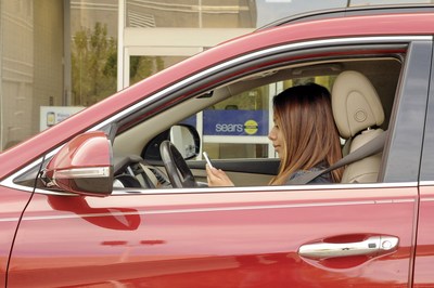 A shopper uses the Sears mobile app, activating its In-Vehicle Pickup service to get her online purchases delivered to her car at the Sears store in Oakbrook, Ill. Retail experts anticipate 2015 will be the most connected holiday ever, with online and in-store shopping experiences becoming more seamless using enhanced mobile features and more integrated retail options.