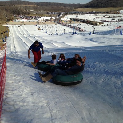 An injured service member and his family prepare to snow tube down the slope.