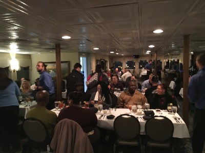 Wounded veterans and guests visit on an evening dinner cruise.