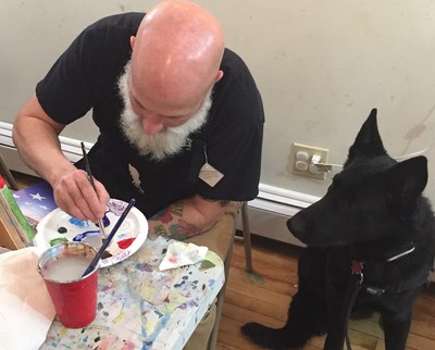 Service dog admires wounded veteran's painting techniques.