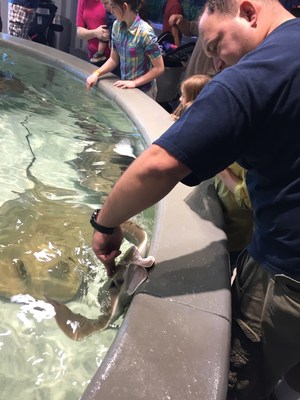 A Wounded Warrior Project Alumnus pets a stingray after a feeding at the Kemah Aquarium, during an Alumni Program event.