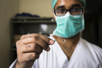 A HelpMeSee surgeon partner in New Delhi, India holds a sample of an artificial lens (IOL) used to restore sight through Manual Small Incision Cataract Surgery (MSICS).