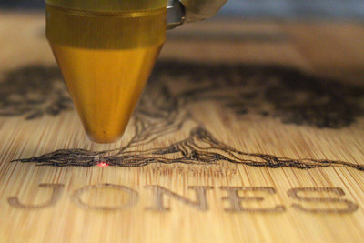 An AP Lazer machine laser engraving an illustration of a tree onto a personalized bamboo cutting board. Photo courtesy of AP Lazer.