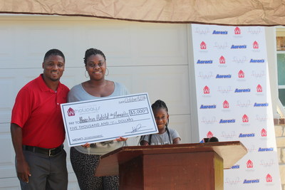 (L to R): Warrick Dunn, Terorah Davis, and daughter Londyn Davis pose in front of the family's new, fully-furnished home made possible thanks to furniture and electronics donations from Aaron's (www.aarons.com). Warrick Dunn Charities' Homes for the Holidays assists single parents in becoming first-time homeowners by providing the materials necessary for long-term stability and the provisions required to ensure that both parent and children can thrive educationally, socially and economically. Aaron's has been a longtime supporter of Warrick Dunn Charities initiatives and began contributing home furnishings, appliances and electronics to the Homes for the Holidays program in 2003.