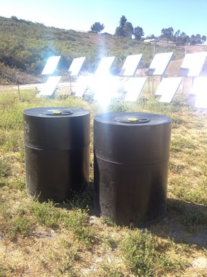 LightManufacturing Sustainably Molded Water Tanks stand in front of Array of H1 Heliostats - each heliostat delivers over 1000 watts of concentrated solar thermal energy for zero carbon plastic molding.